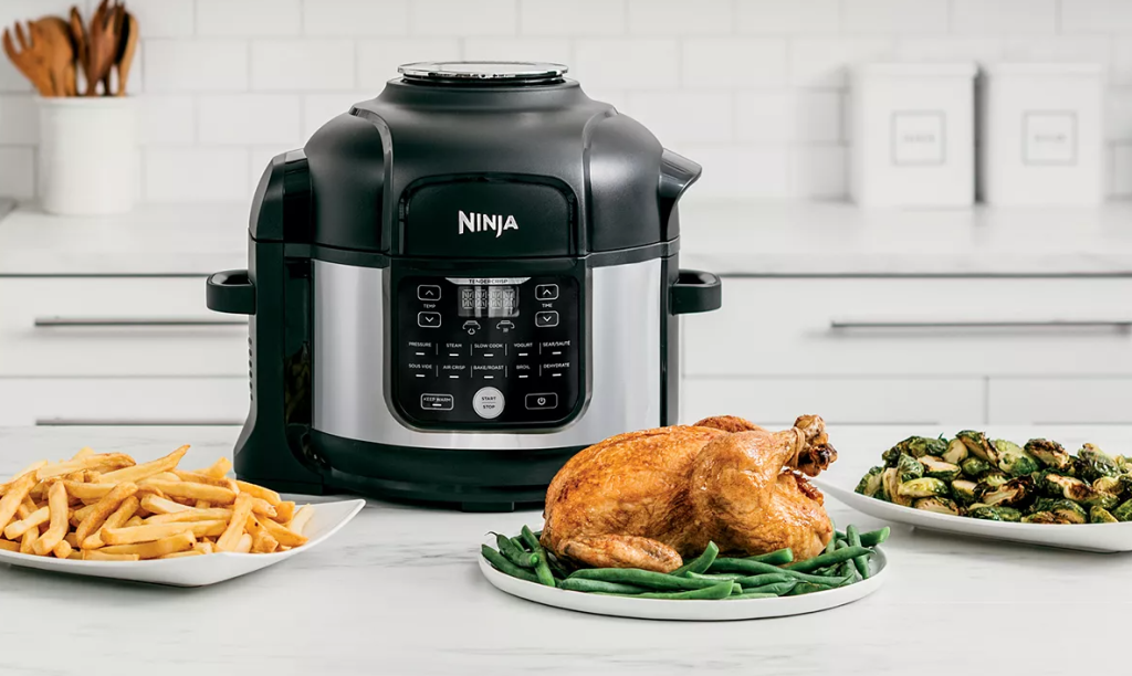 Ninja pressure cooker with plates of food in front of it