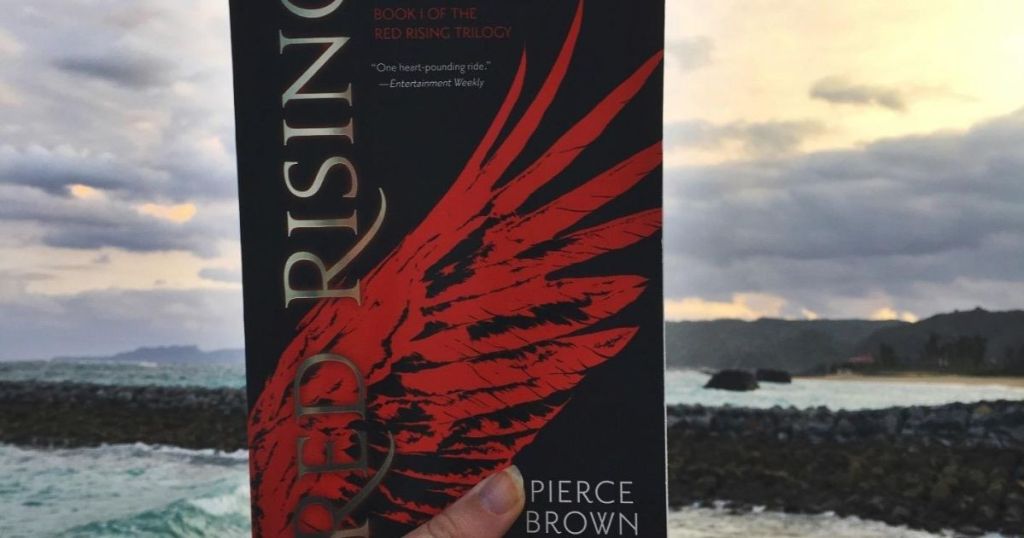 hand holding Red Rising by Pierce Brown outdoors