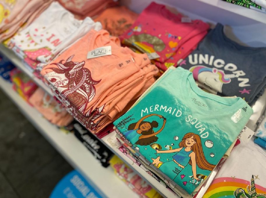 girls graphic tees folded on display table in store