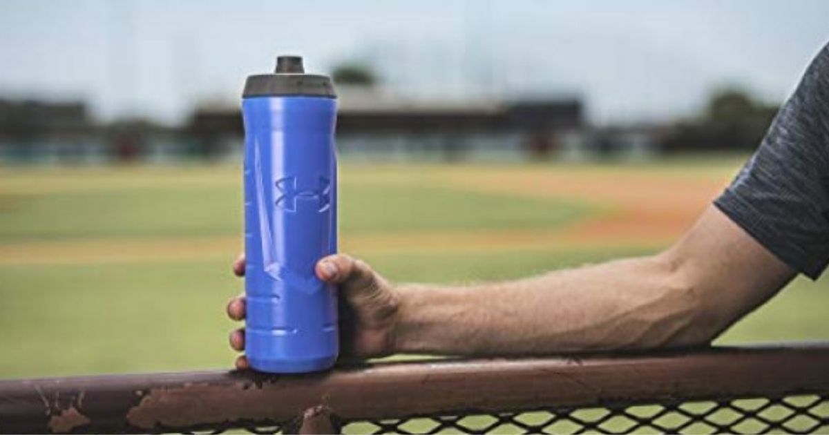 person holding blue Under Armour Squeezable Water Bottle on fence