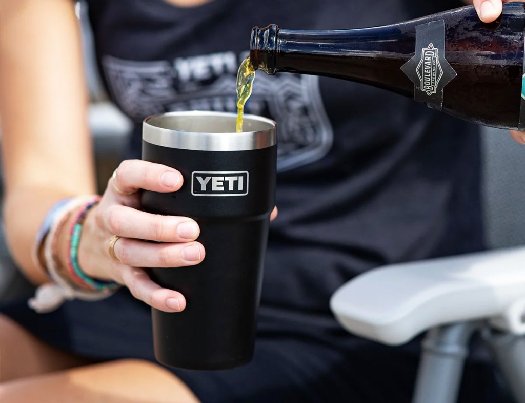 person pouring wine into a black yeti pint cup