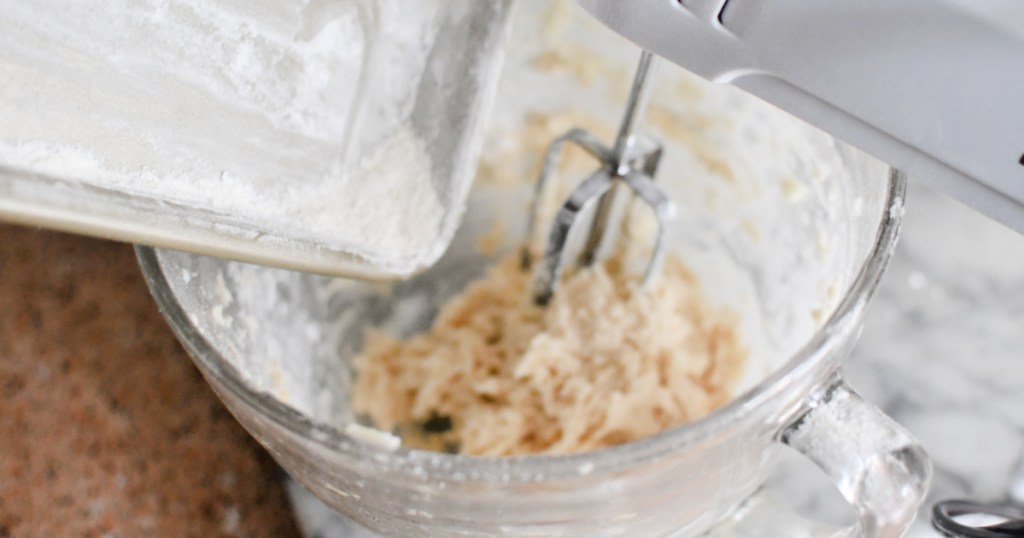 adding flour into bowl of butter, vanilla, and sugar