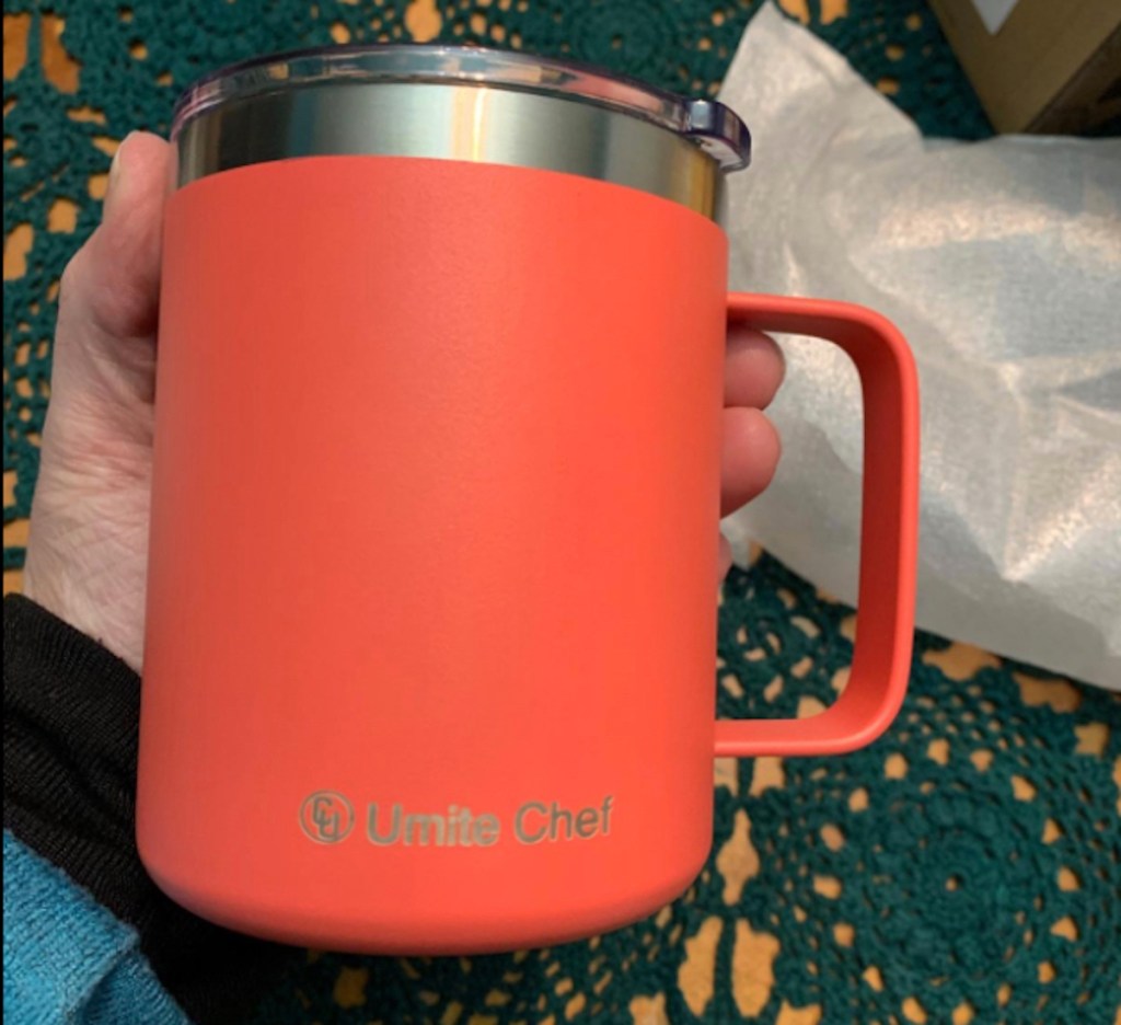 hand holding a bright orange coffee mug 