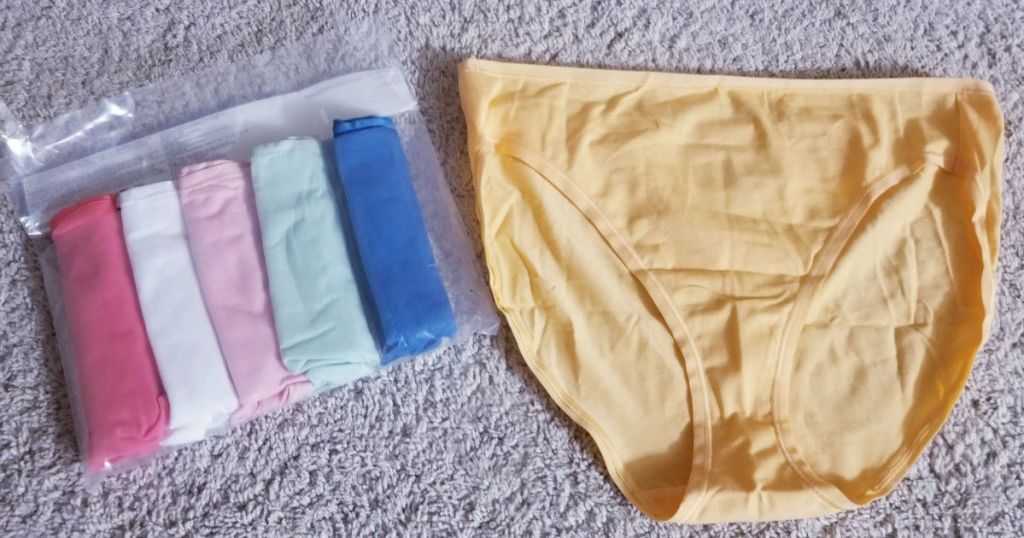 yellow bikini briefs next to 5 pairs of rolled up underwear in packaging