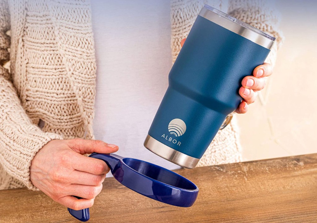 hand holding blue travel mug and detachable handle