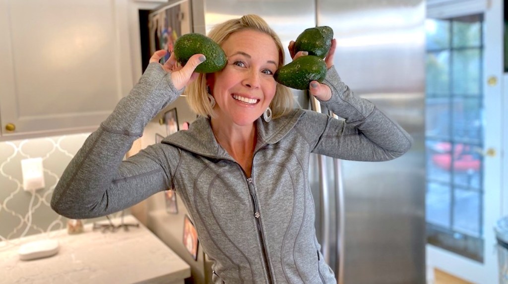 woman smiling holding avocados to her head