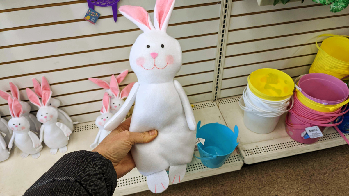hand holding a fabric easter bunny in front of a store shelf