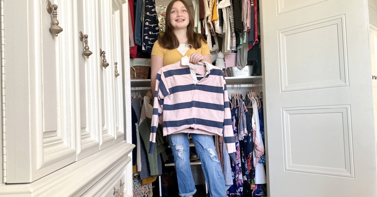 girl holding shirt from Poshmark next to closet 