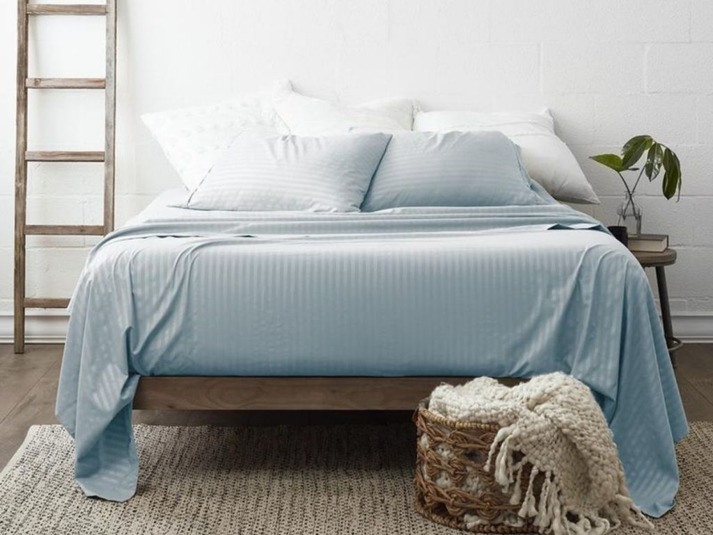white and light blue striped sheets on bed