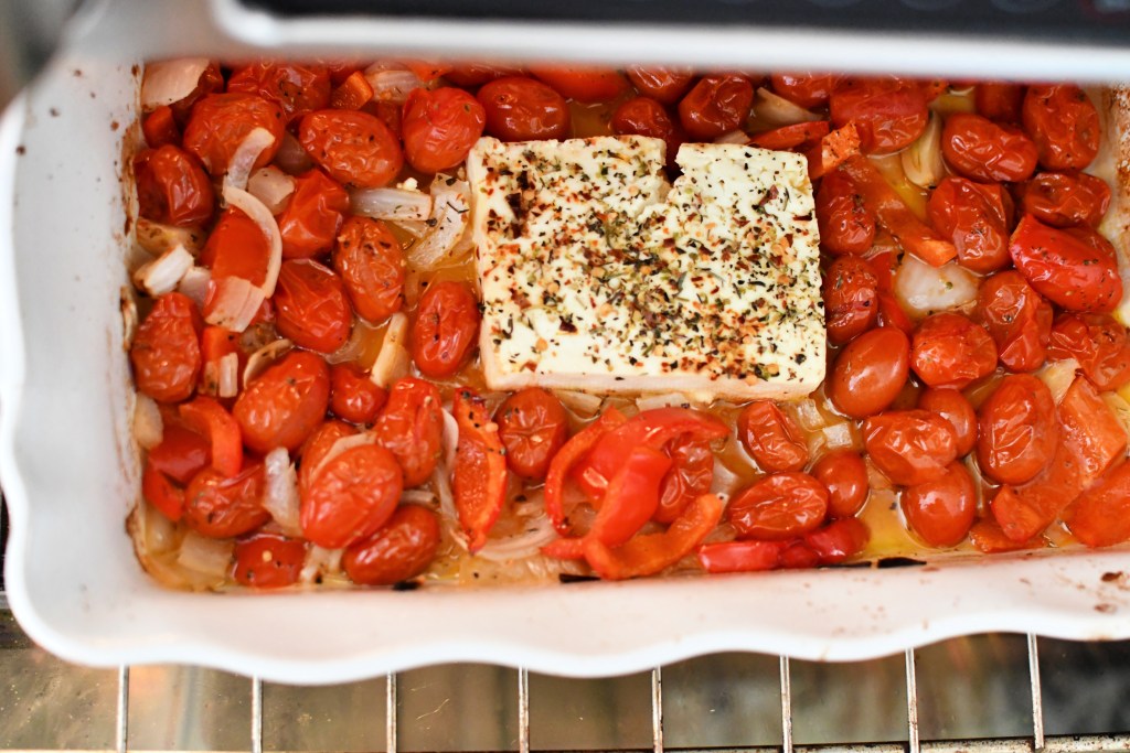 melted feta and roasted tomatoes in a baking dish 