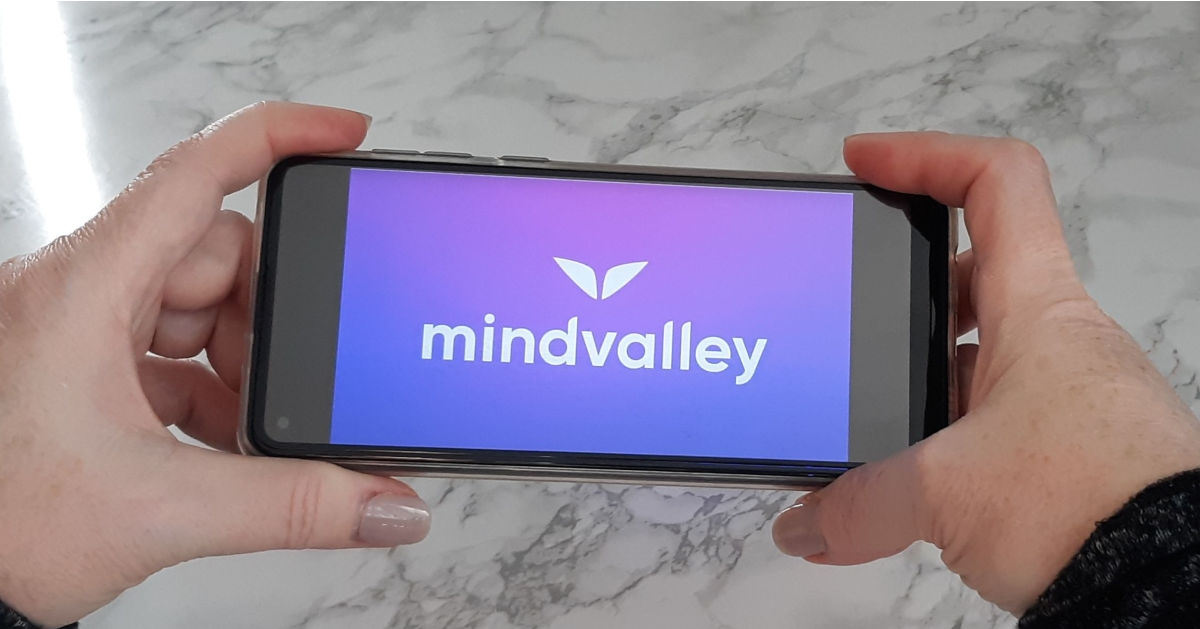 holding a phone open to Mindvalley App