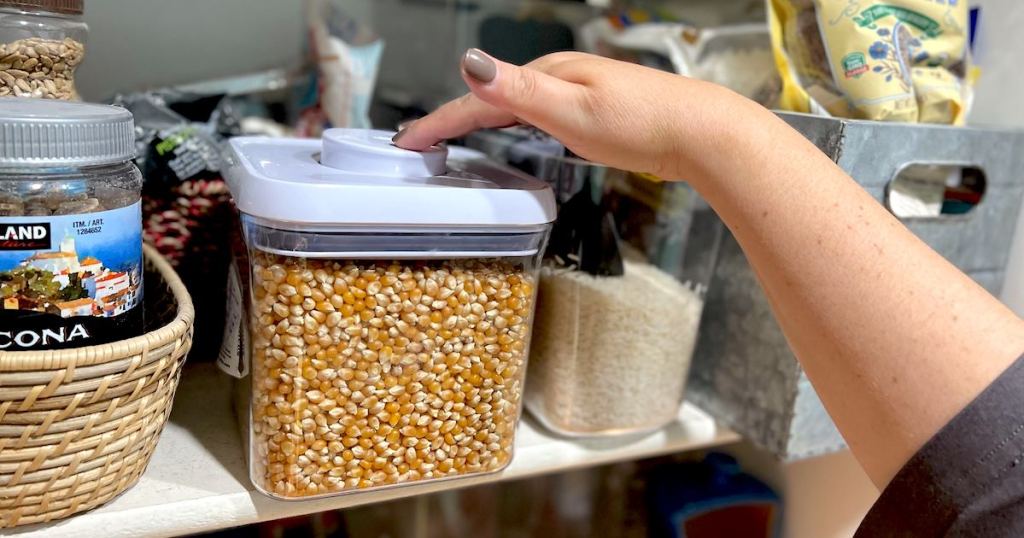 hand pushing down on oxo pop container with corn kernals