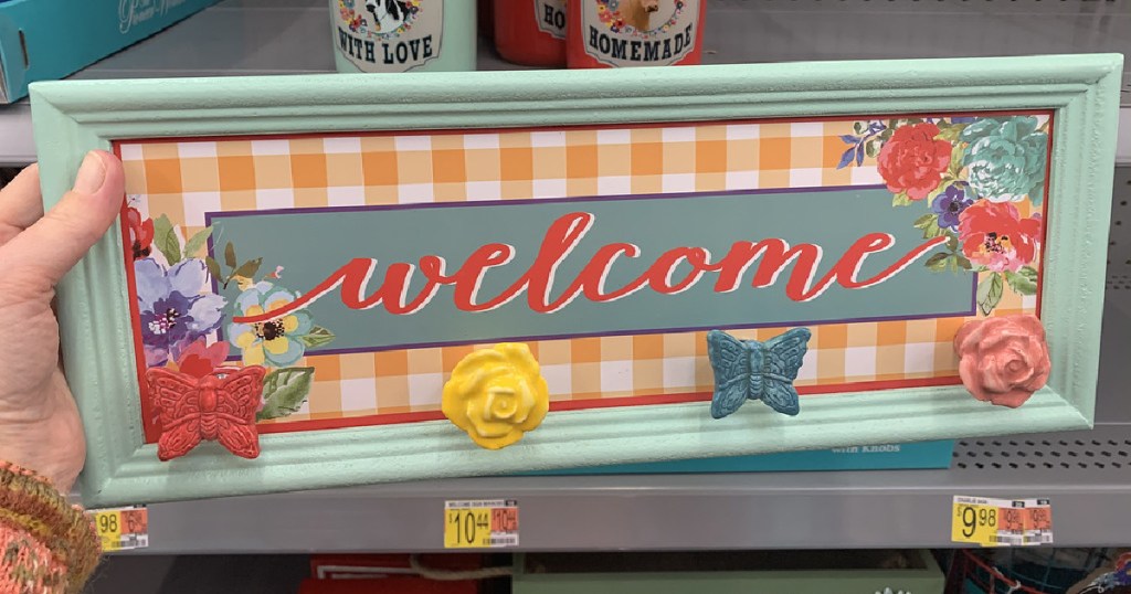 hand holding up a welcome sign with colorful finials in a store