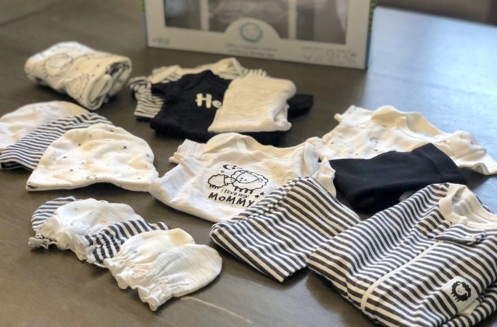 tons of black and white gender neutral baby clothes laying on table
