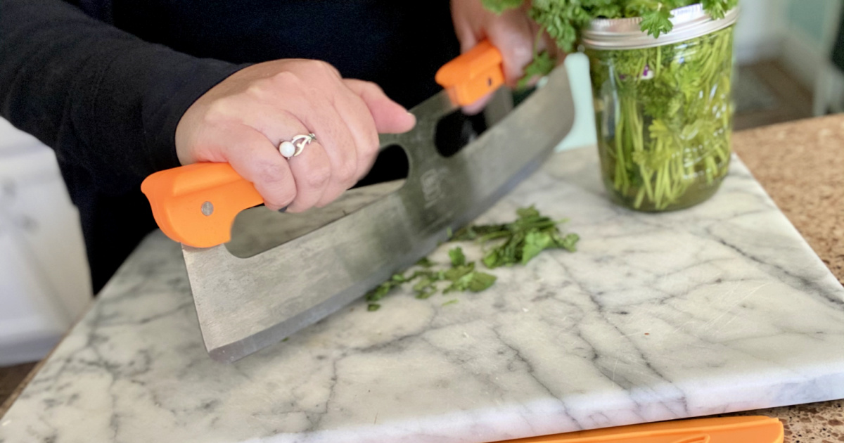 woman mincing herbs with pizza slicer