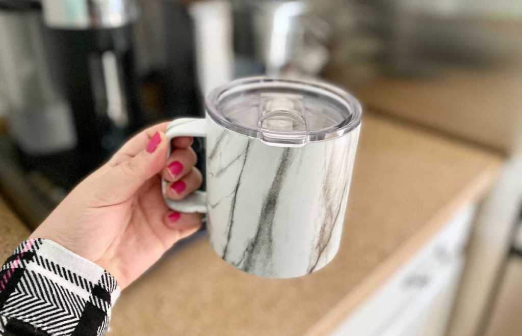 hand holding marble colored coffee travel mug