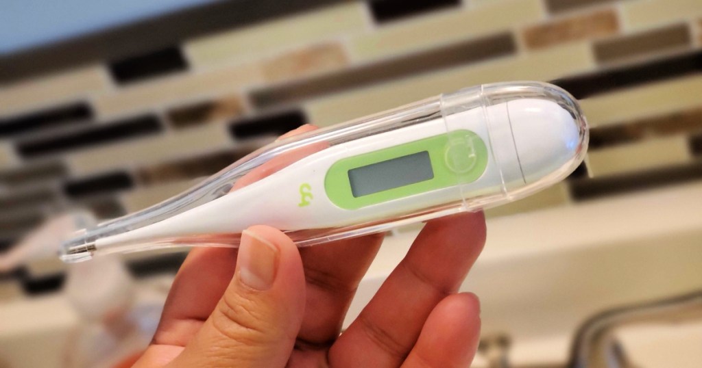 person holding white and green thermometer