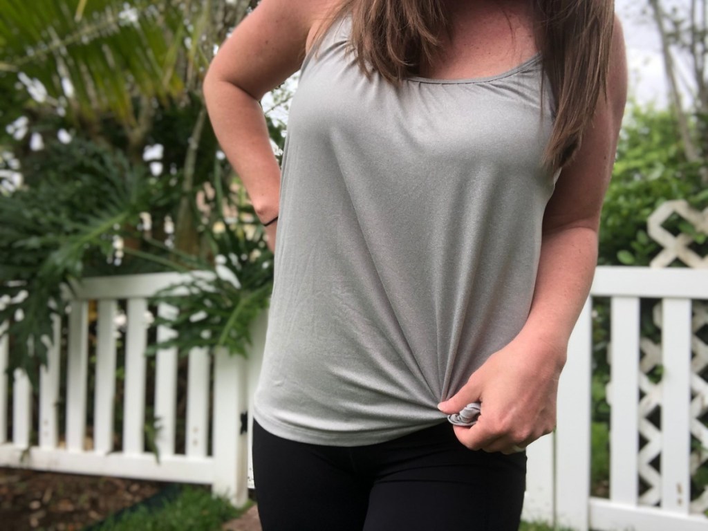 woman wearing grey tank top outside by white fence