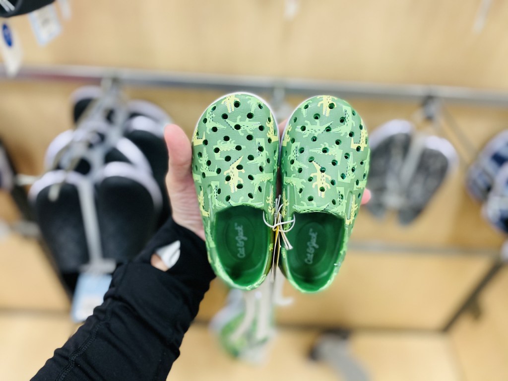 Hand holding up a pair of Alligator Shoes