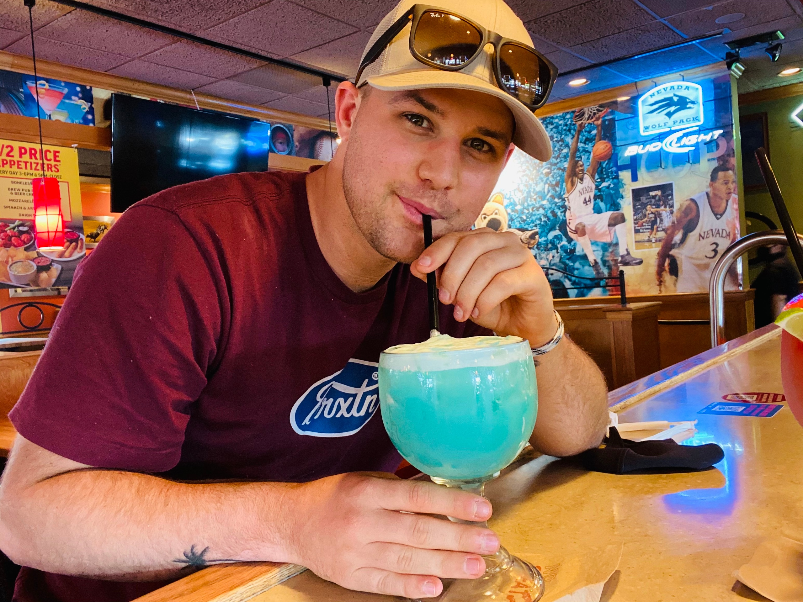 man drinking blue cocktail in restaurant