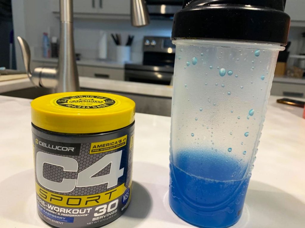 container of c4 preworkout on counter next to shaker bottle with blue liquid inside