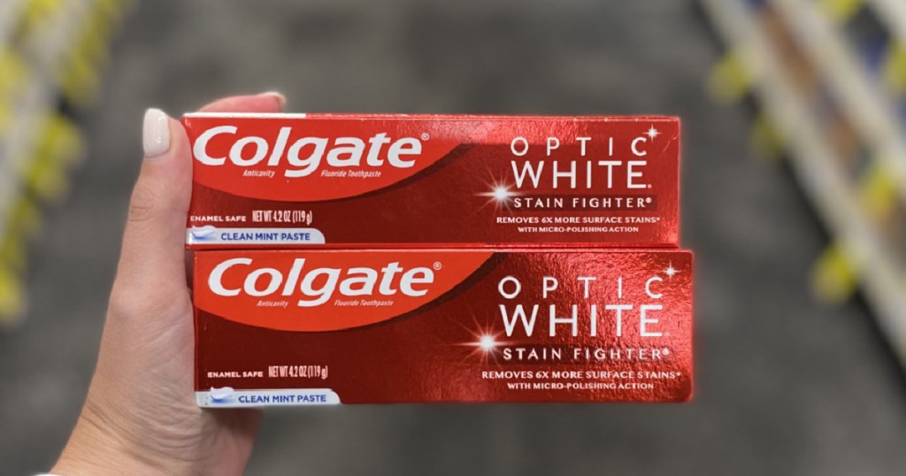 hand holding two Colgate Optic White toothpastes