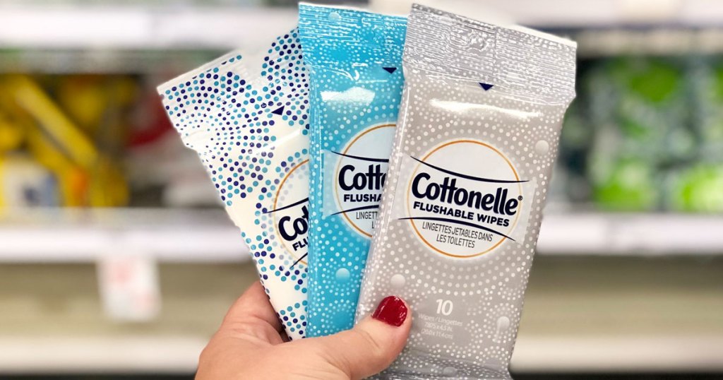 person holding up three packages of cottonelle wipes