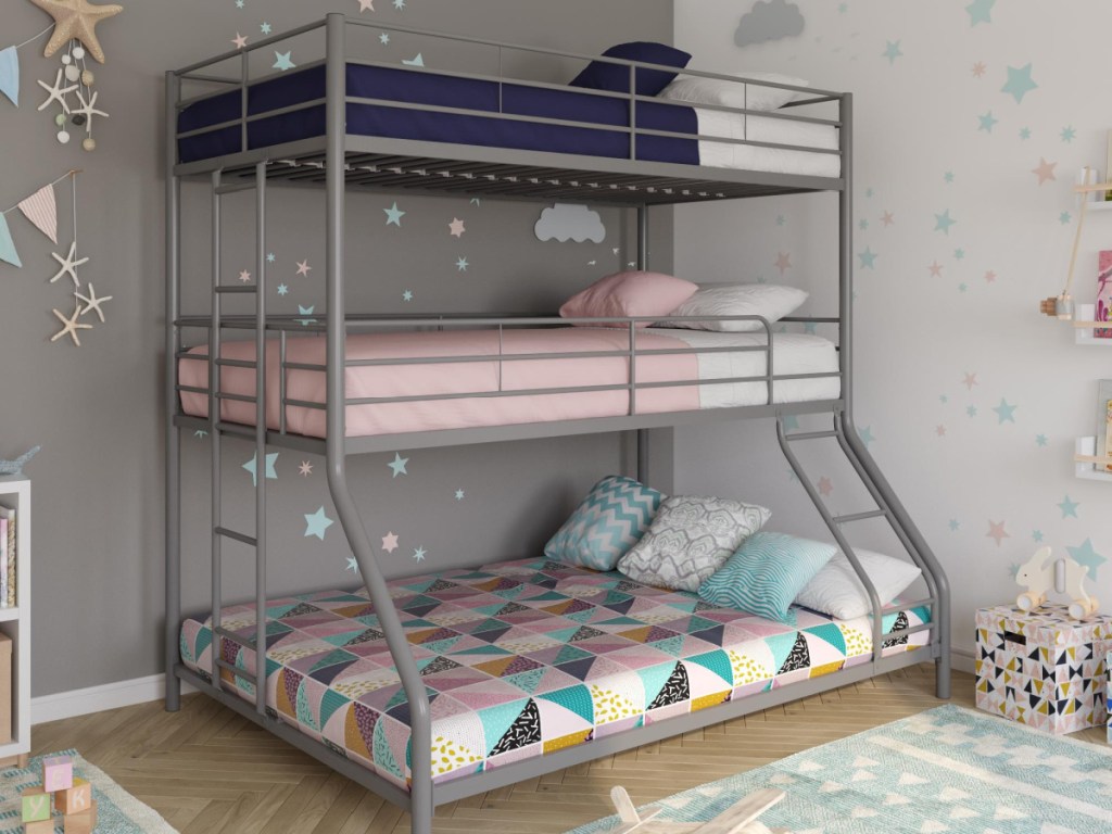 kids triple bunk bed with pink, blue, and pink and teal patterned sheets in bedroom