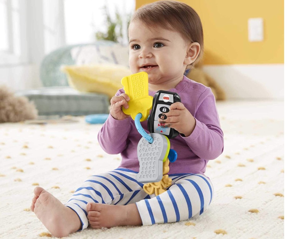 baby on floor playing with toy keys