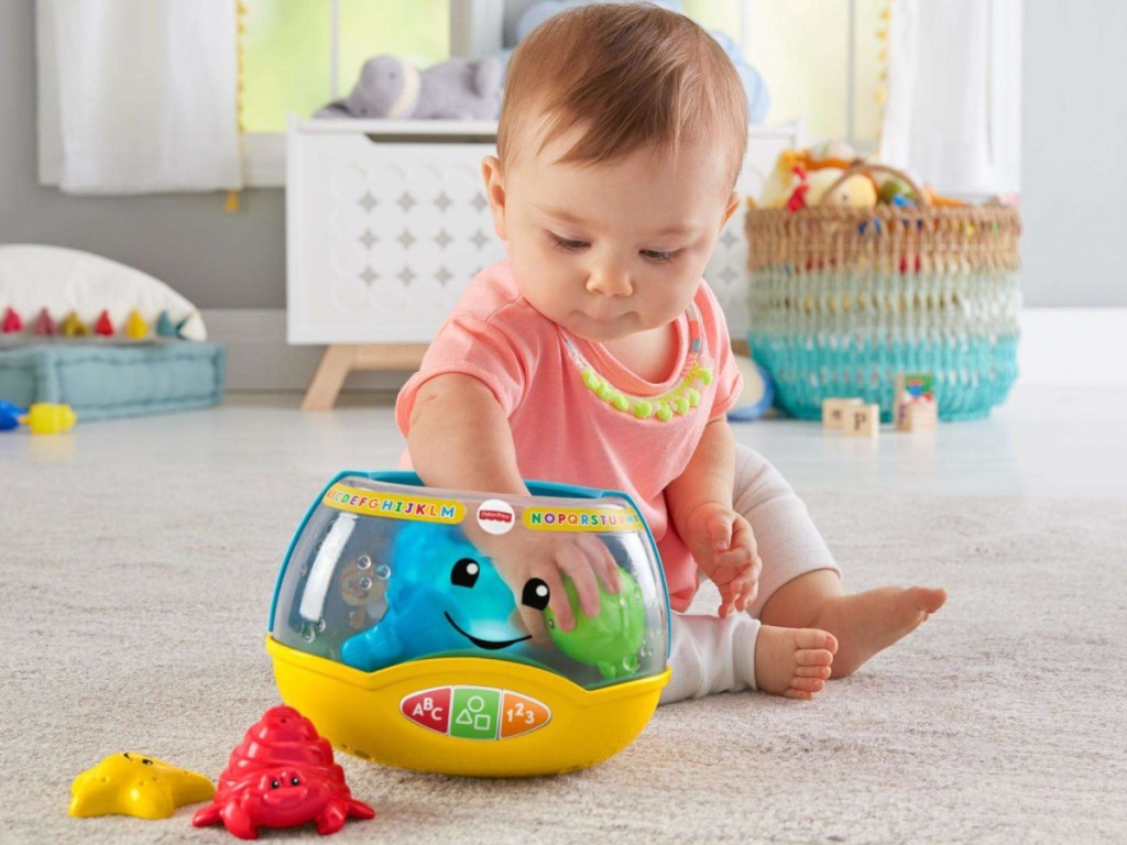 baby sitting on the floor playing with fisher price magic fishbowl