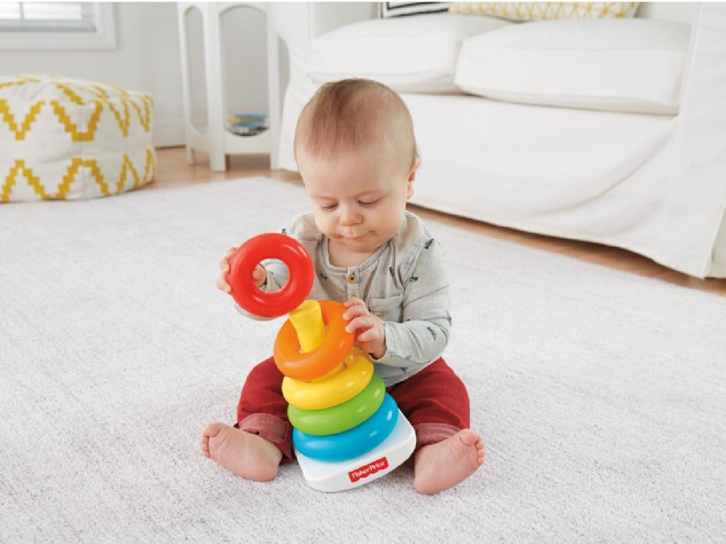 baby sitting on the floor with fisher price stacking rings