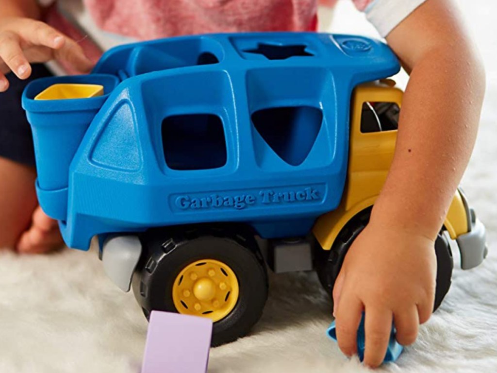 small child playing with green toys truck shape sorter
