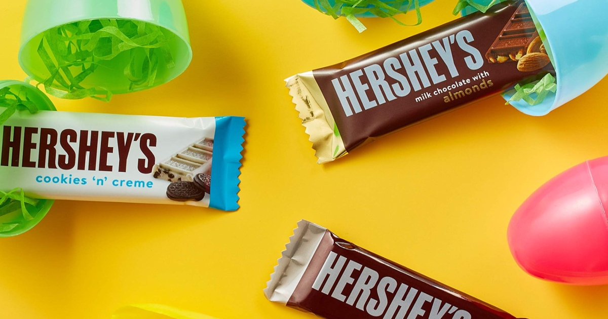 two pieces of individually wrapped Hershey's chocolate bars minis and one Hershey's Cookies & Creme with plastic Easter eggs nearby 