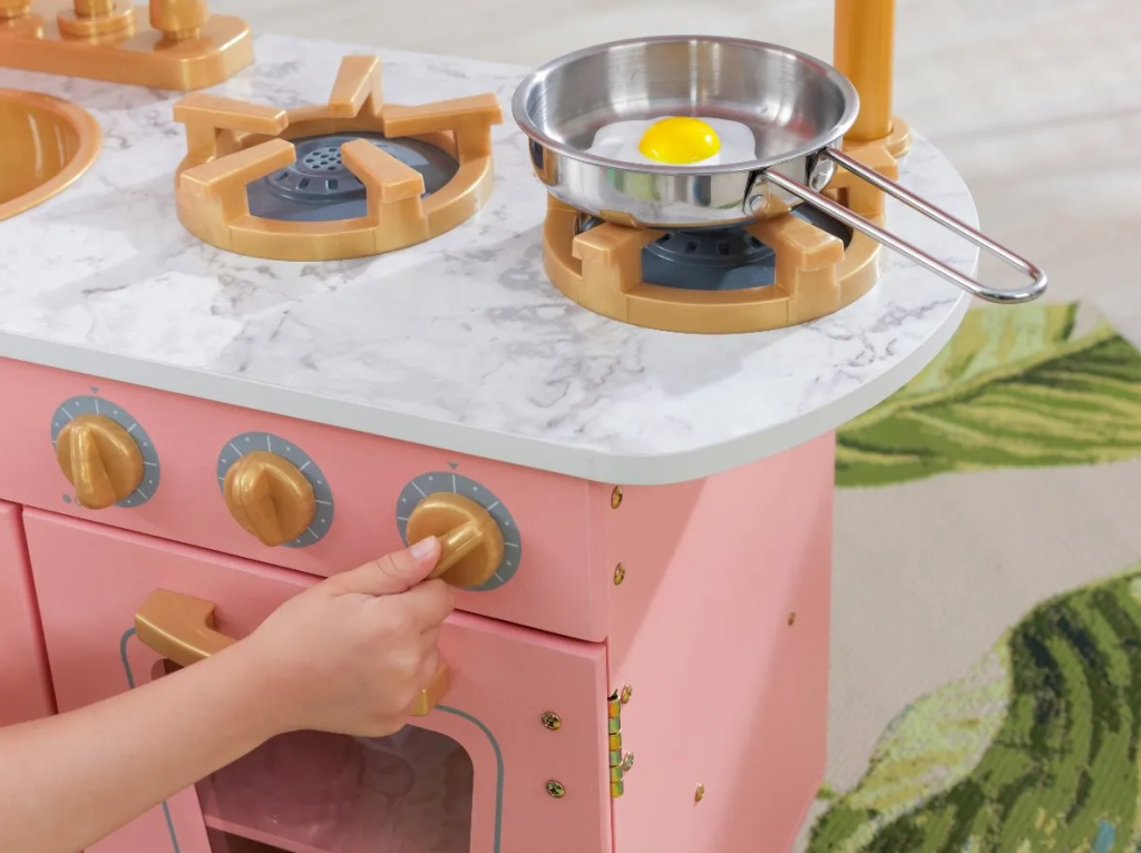 hand turning a knob on a toy kitchen
