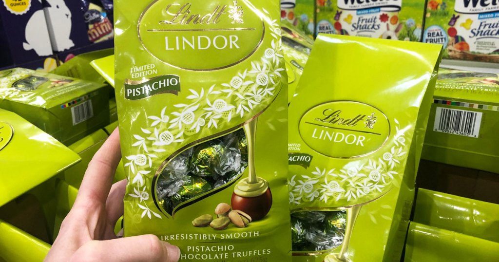 person holding a green bag of Lindt Pistachio Truffles