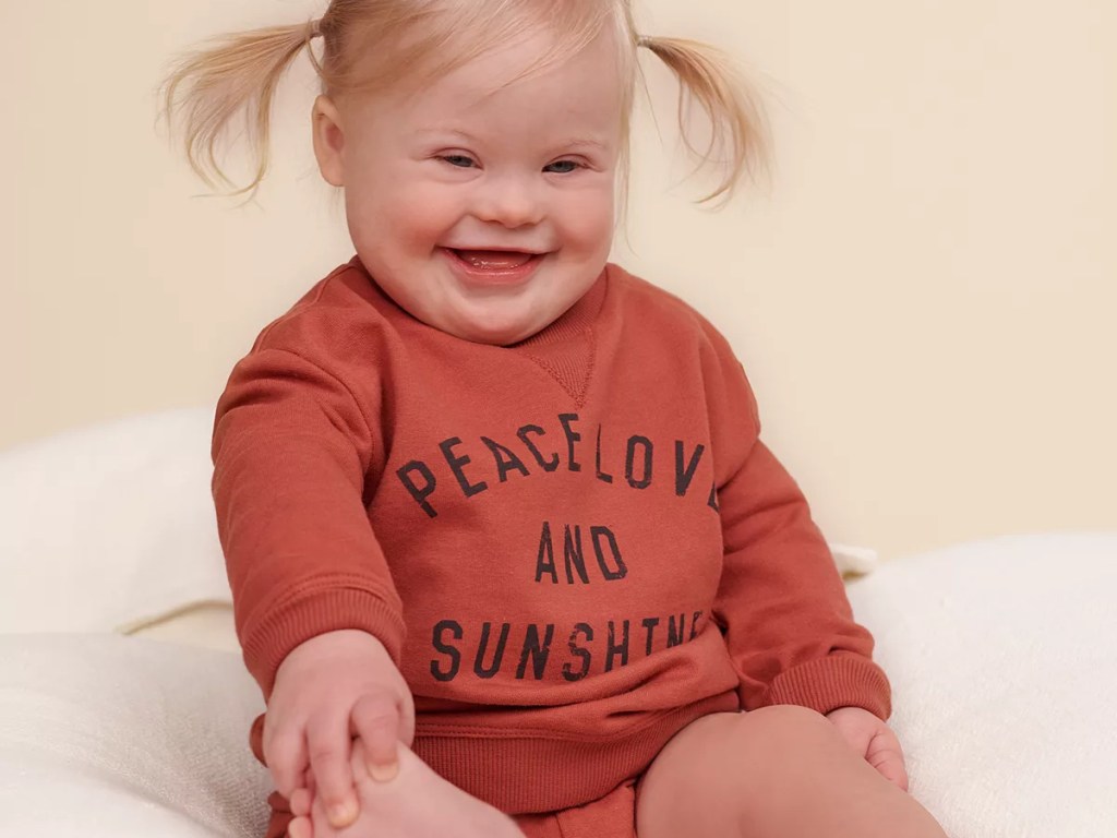 baby girl sitting on floor in graphic sweatshirt