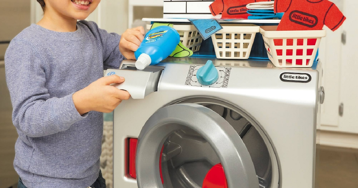 young boy playing with a toy washing machine