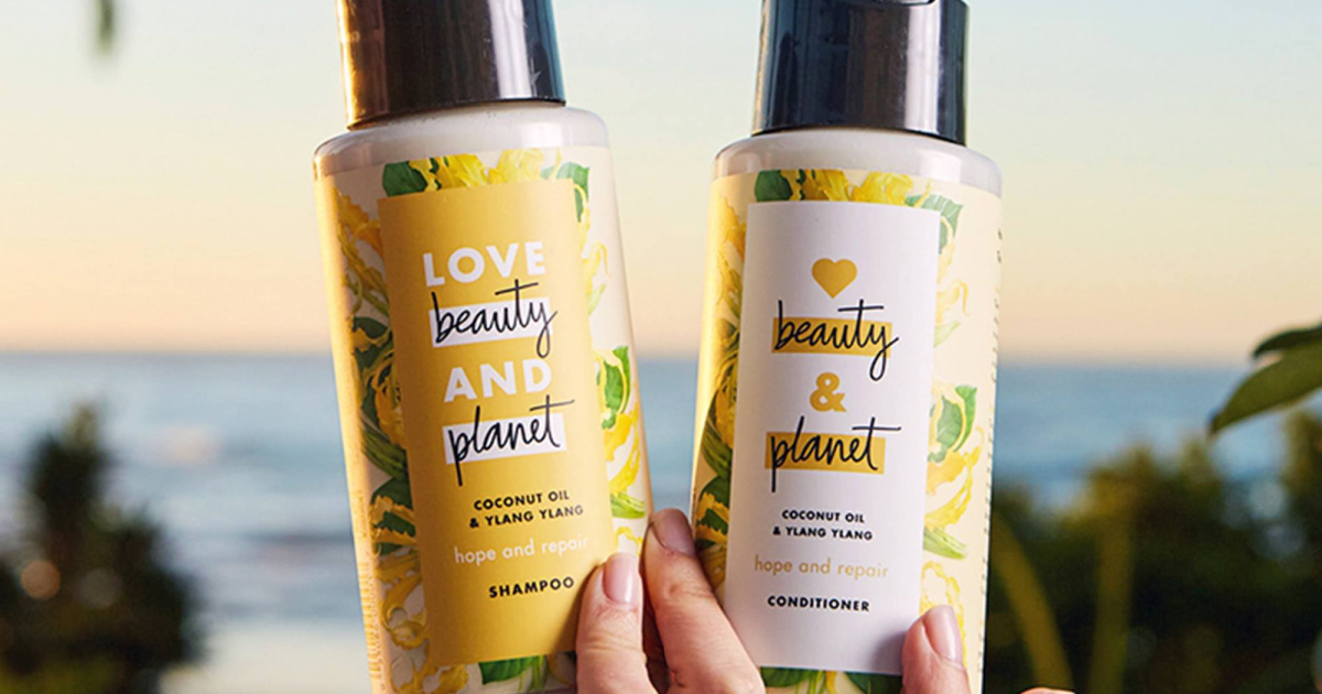 hand holding bottle of shampoo and conditioner with beach landscape in background