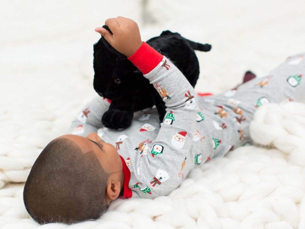 little boy laying on his back holding a stuffed black lab puppy