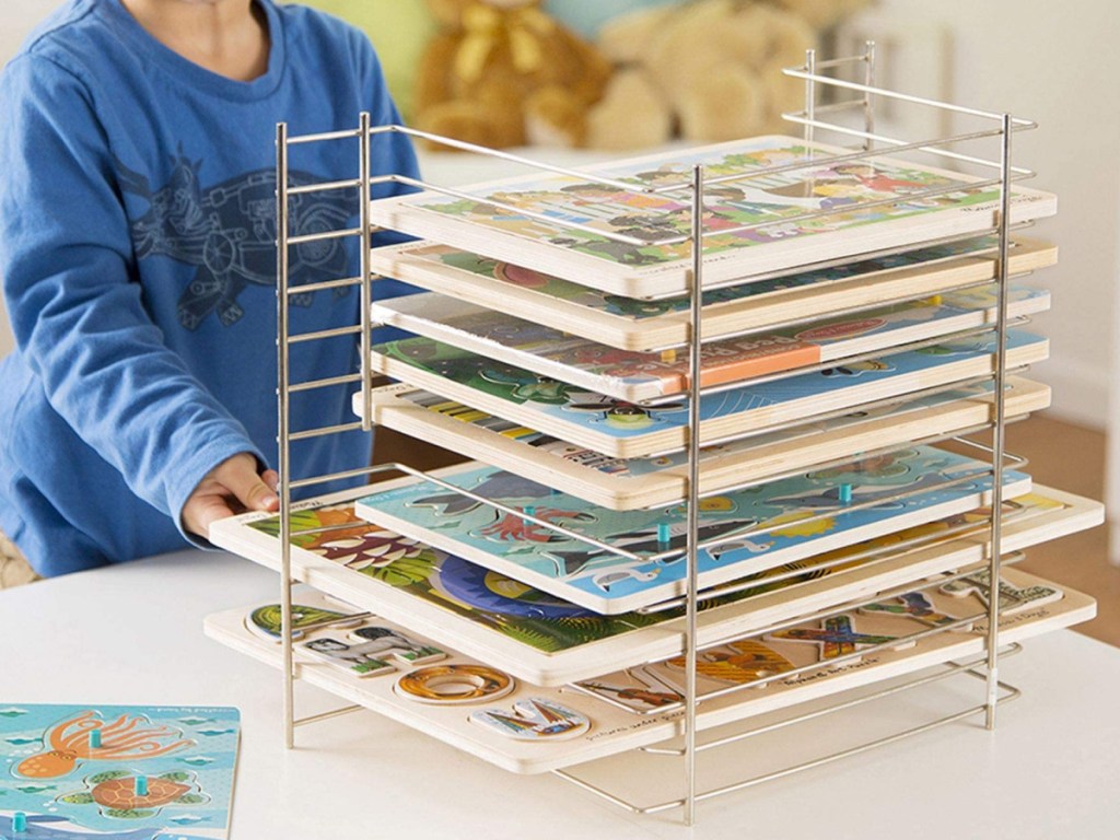 boy standing next to a melissa and doug puzzle rack 