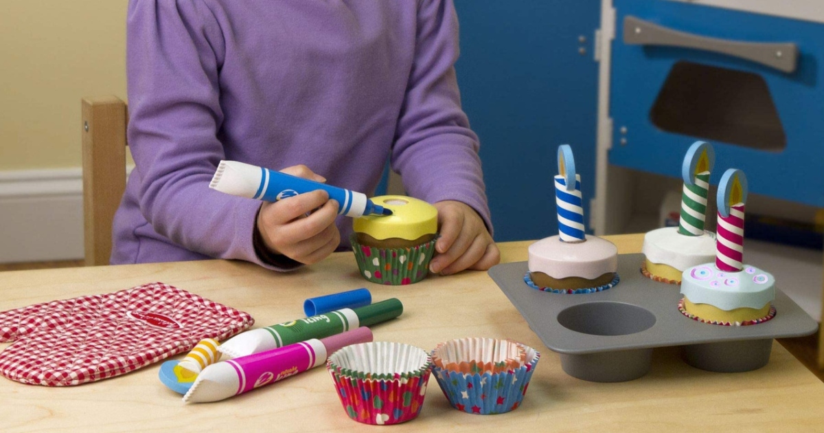 girl at a table playing with a wooden cupcake set