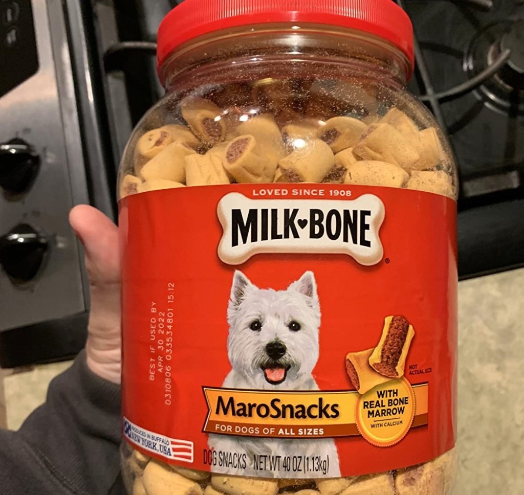 hand holding a container of dog treats
