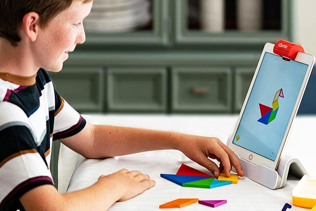 boy using puzzle pieces to create shape displayed on tablet