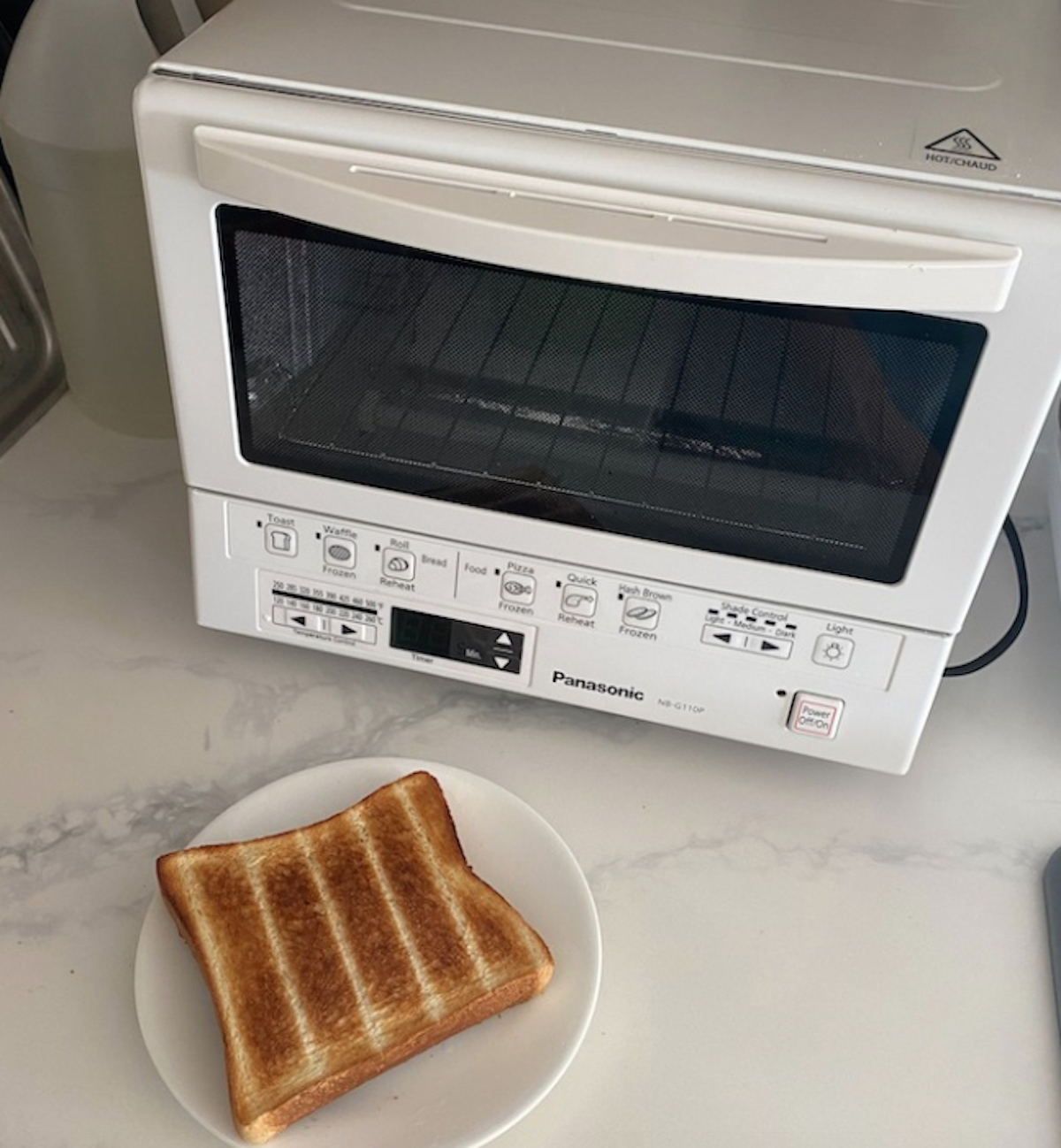 white kitchen appliance on marble counter with piece of toast