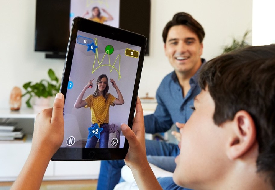 child and adults using tablet to play drawing game in living room