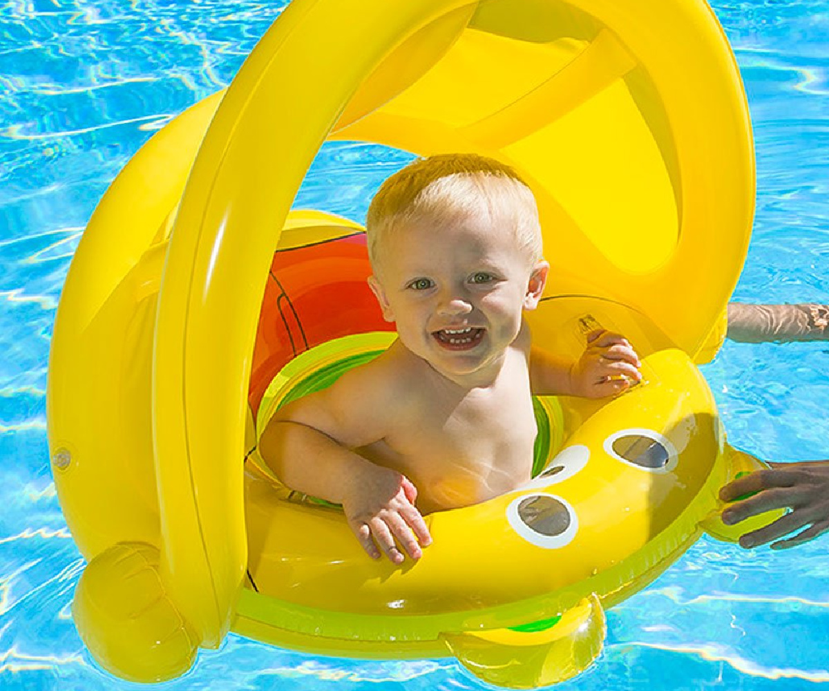 smiling baby boy in a bright yellow canopied pool flat