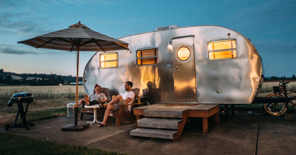 2 adults sitting in front of an airstream camper