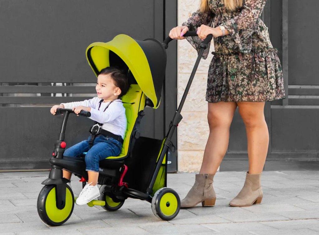 woman pushing child in black and green trike stroller