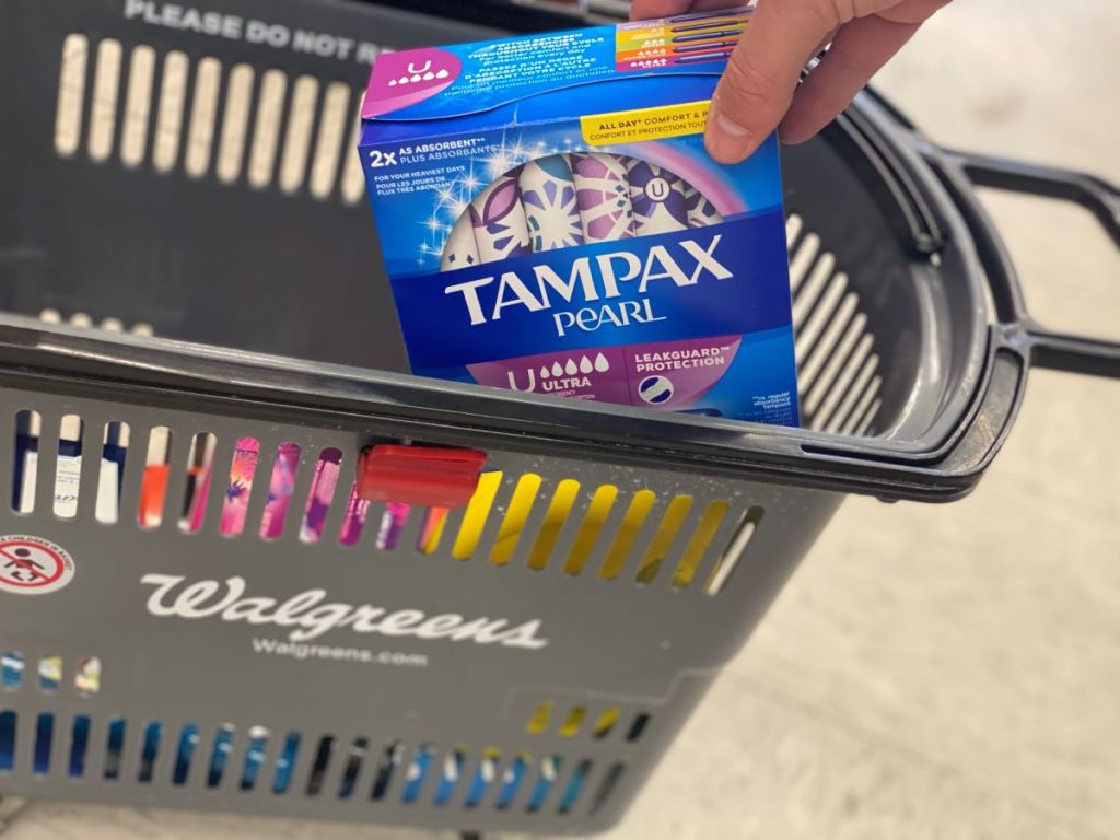 hand putting tampax tampons in a basket