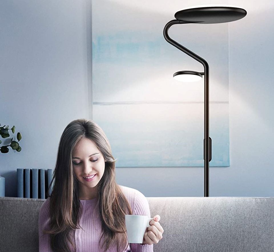 woman holding a cup of coffee with a lamp behind her